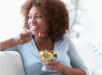 woman with healthy skin eating a bowl of fruit