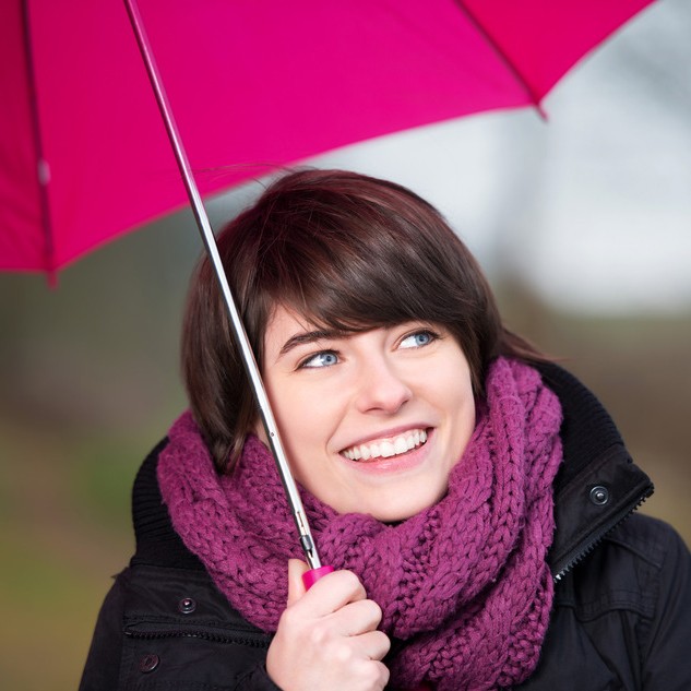 Happy woman under a pink umbrella and wrap