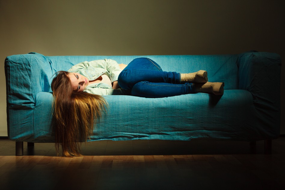 Young sad stressed woman lying on couch at home