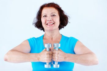 middle-aged female doing physical exercise with dumbbells