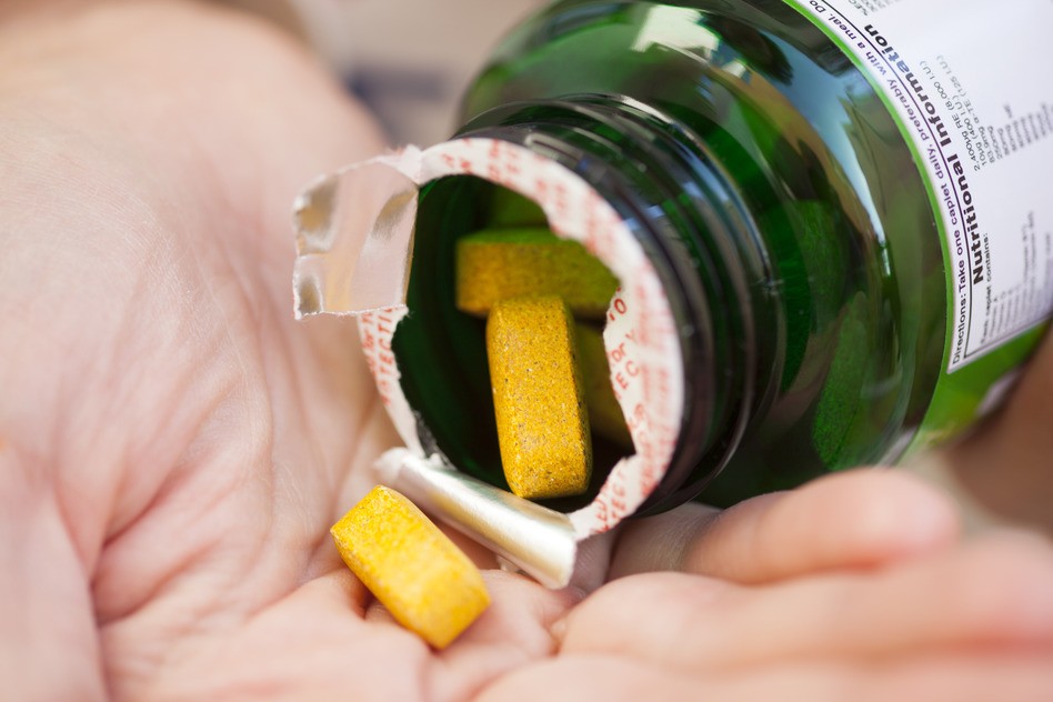 Hand with Multivitamins pouring from a bottle